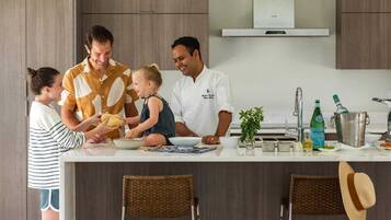 A modern kitchen with a central island, stainless steel appliances, and a dining area with wicker chairs.