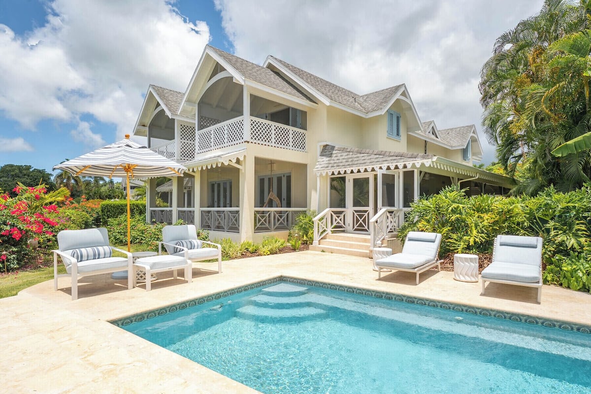 A large house with a swimming pool, outdoor furniture, and lush greenery.