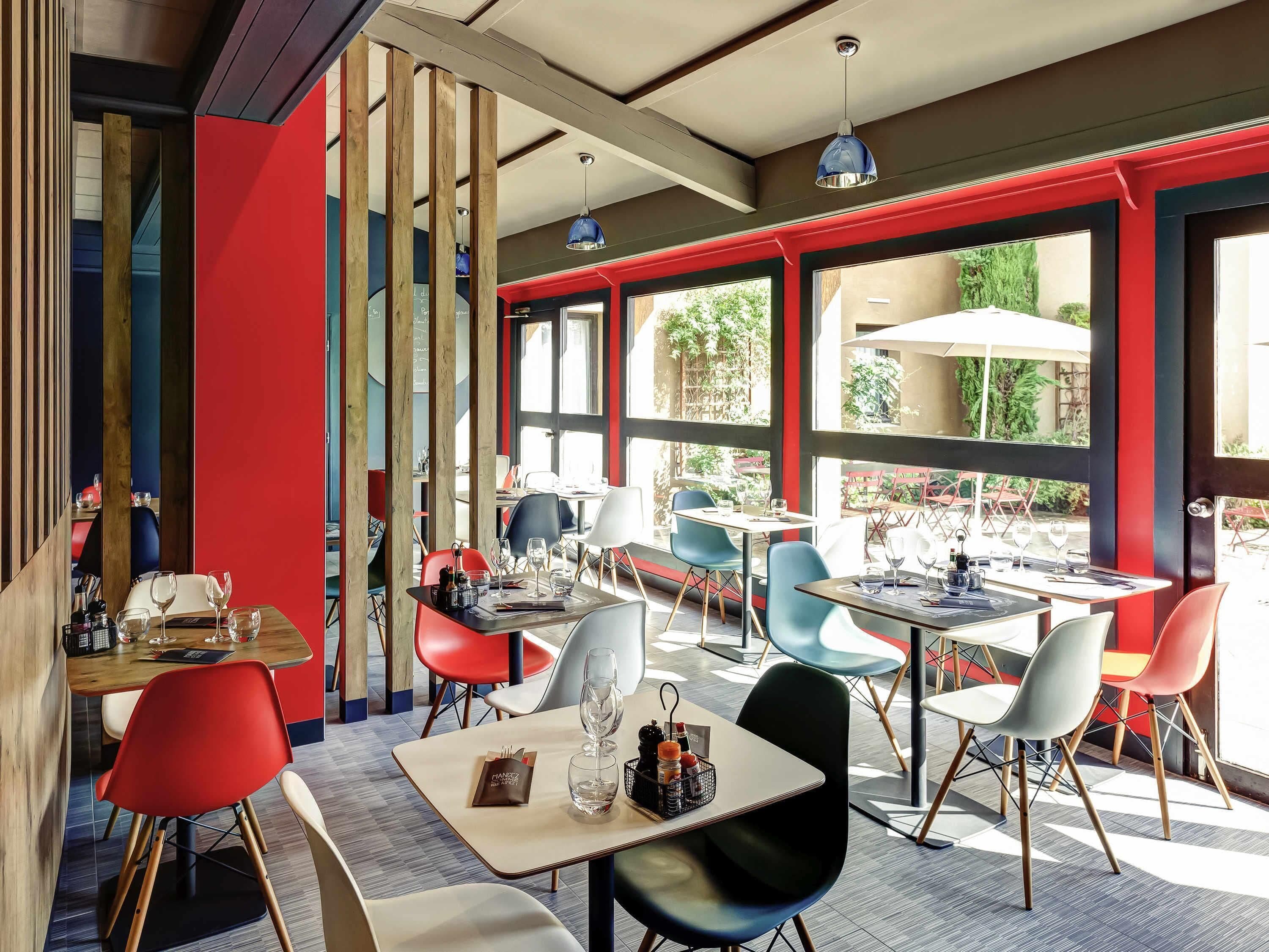 Un restaurante con varias mesas y sillas, amplios ventanales y vistas al exterior.