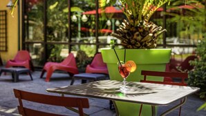 A table with a drink and a potted plant in the background. - ibis Lyon Nord (Dardilly)