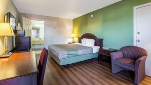 A hotel room with a bed, a desk, a chair, a TV, and a lamp. - Americas Best Value Inn Edgewood (Edgewood)