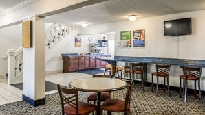 A hotel lobby with a bar area, a staircase, and a kitchen in the background. - Americas Best Value Inn Edgewood (Edgewood)