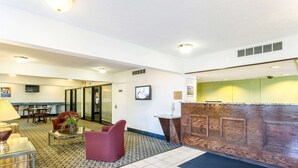 A lobby with a reception desk, seating area, and a television screen. - Americas Best Value Inn Edgewood (Edgewood)