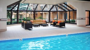 A pool area with a glass-enclosed patio, furnished seating, and a clear view of the surrounding buildings.