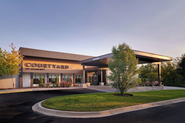 A Courtyard by Marriott hotel with a modern entrance, a covered parking area, and well-maintained landscaping.