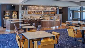 A modern bar area with a counter, seating, and a menu display.