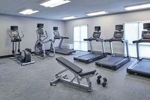 A gym with treadmills, elliptical machines, and a bench.