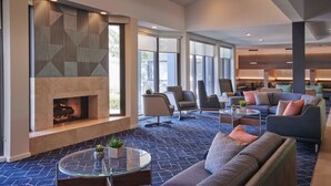 A modern living room with a fireplace, comfortable seating, and large windows.