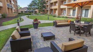 A courtyard with outdoor furniture, a pathway, and a building with balconies.