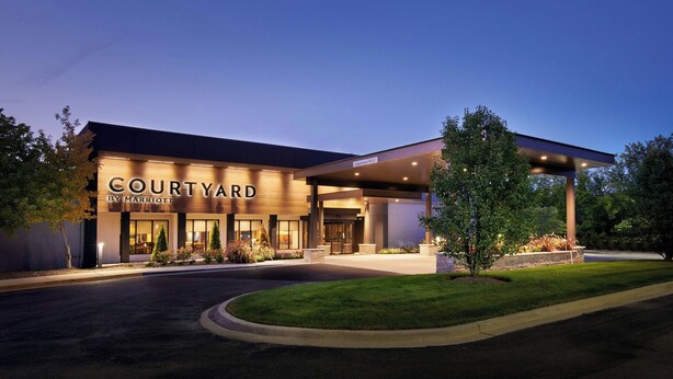 A Courtyard by Marriott hotel with a well-lit entrance, landscaped surroundings, and a modern architectural design.