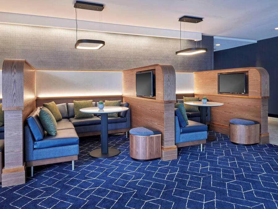 Un'area lounge moderna con divani, tavolini e televisori integrati.