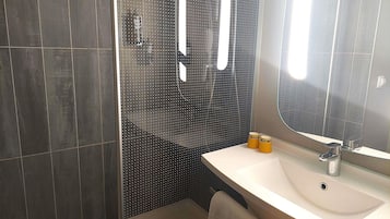 A modern bathroom with a shower, a sink, and a mirror.