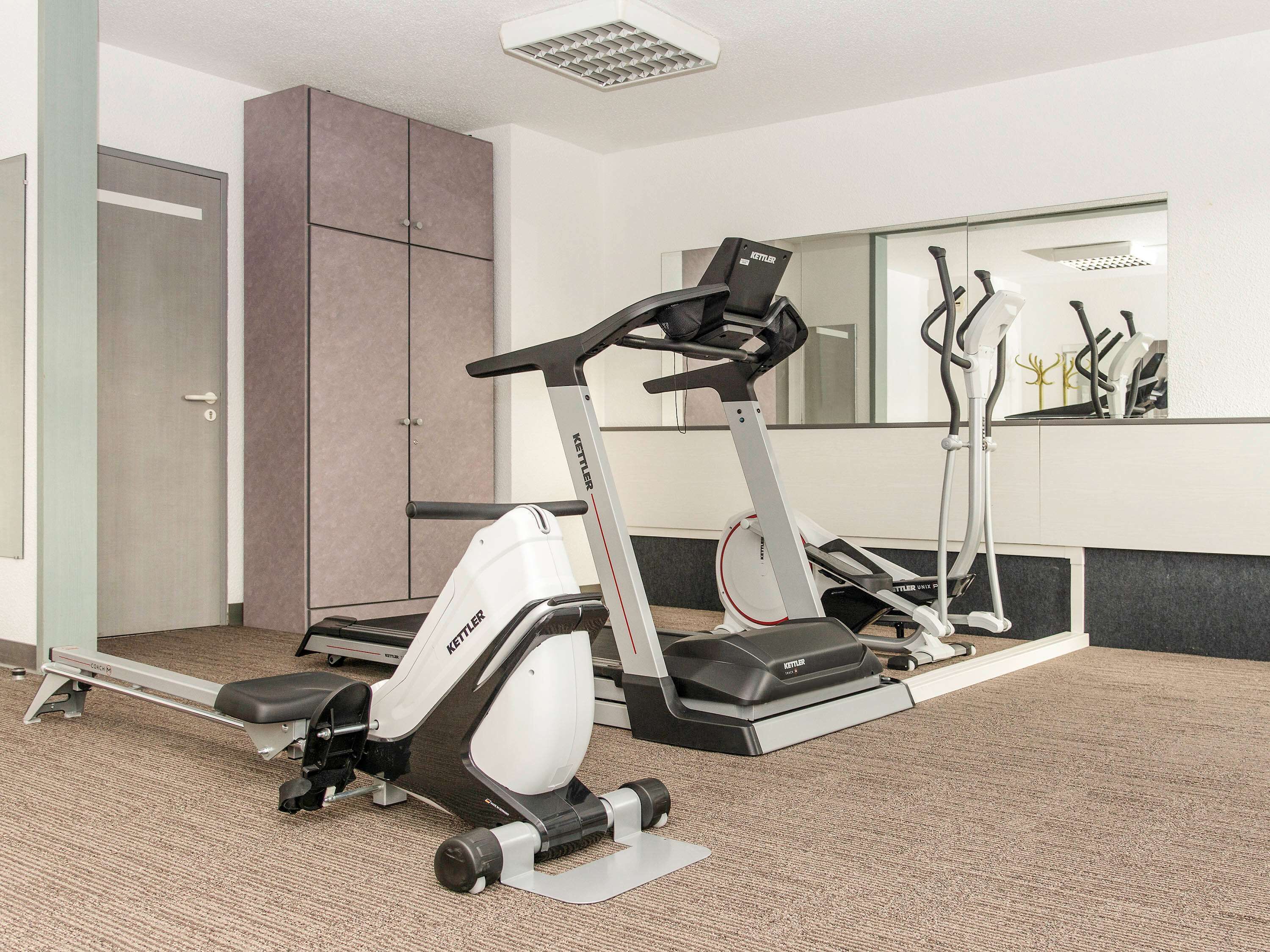 A fitness area with an elliptical machine, a treadmill, and a mirror.