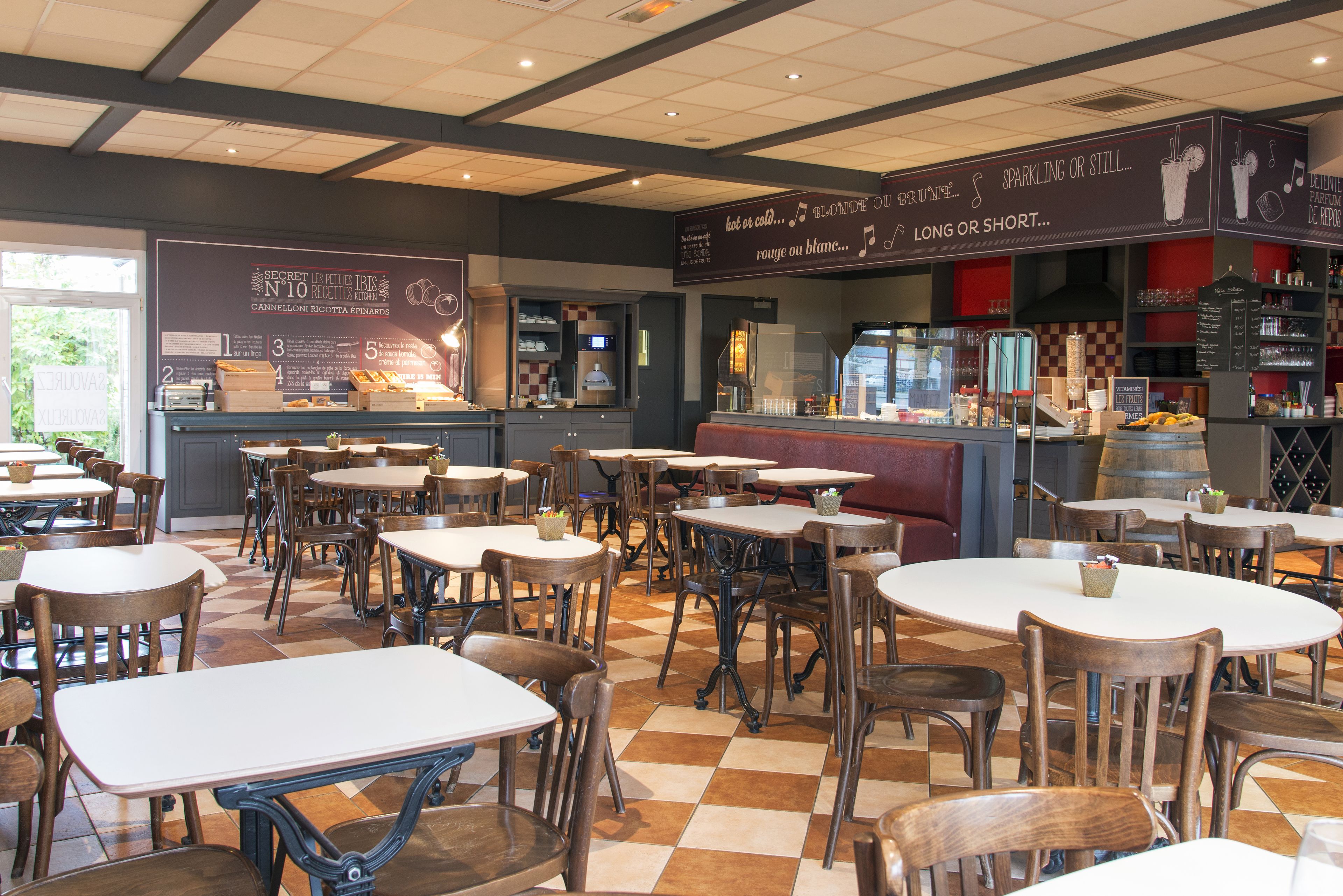 Een restaurantinterieur met meerdere tafels en stoelen, een balie met een menukaart en een wijnrek op de achtergrond.