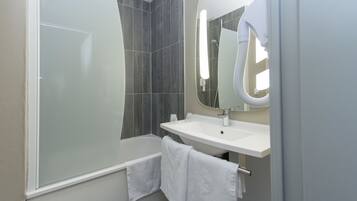 A modern bathroom with a glass-enclosed shower, a white sink, and a large mirror.
