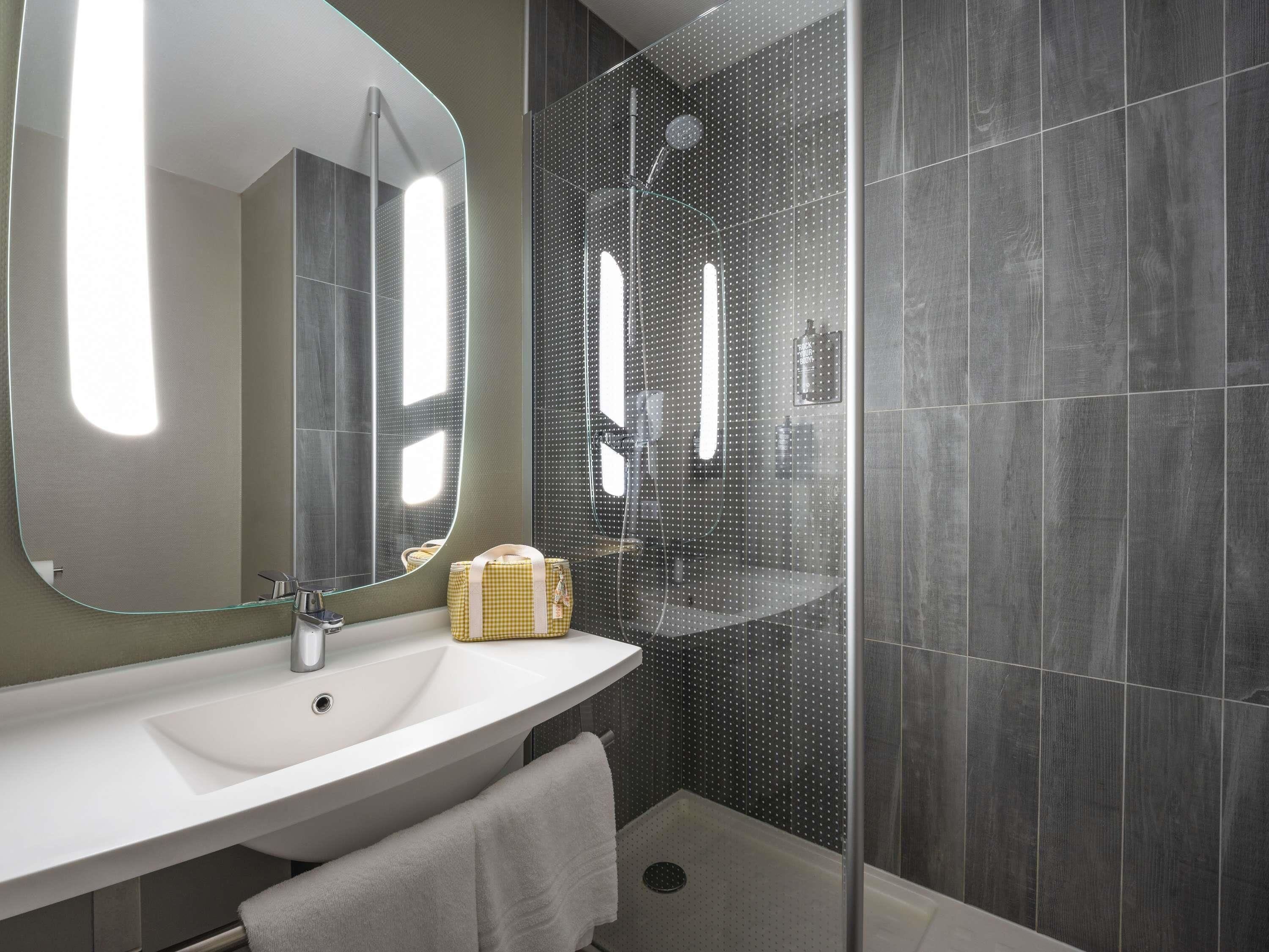 Un baño moderno con un espejo grande, un lavabo y una zona de ducha.
