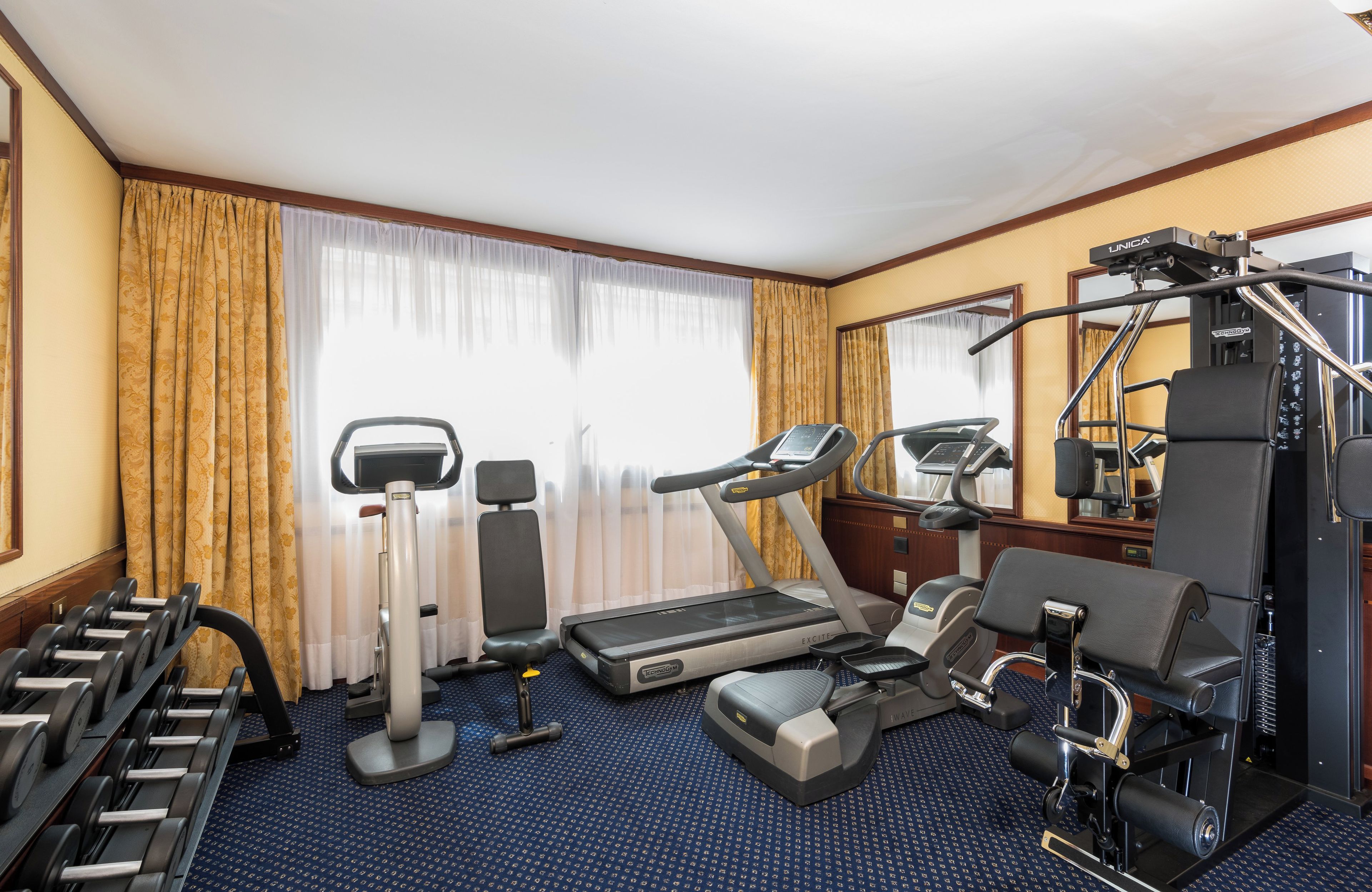 Quarto de hotel com esteira ergométrica, elíptico e aparelhos de musculação.