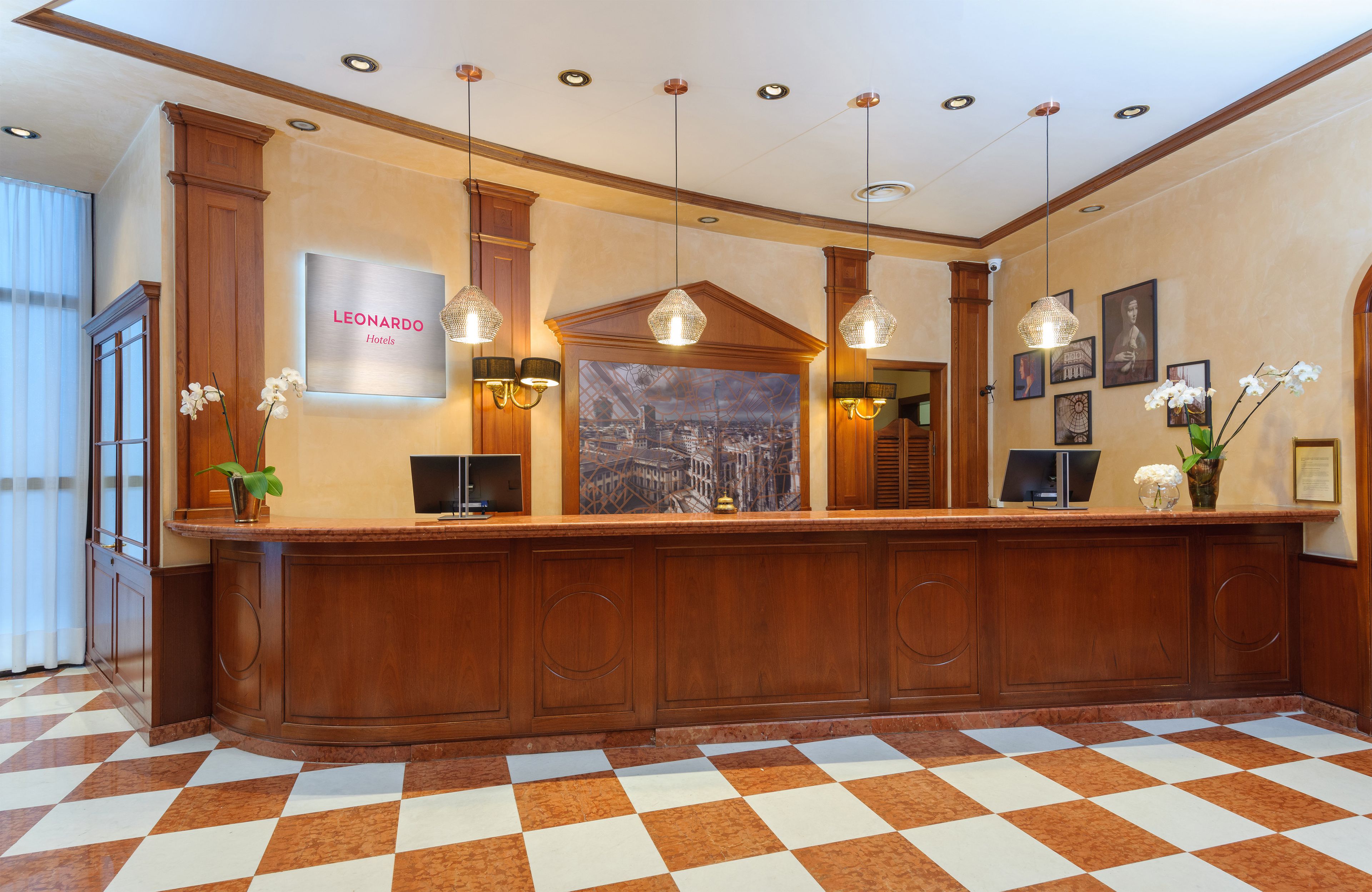 A hotel reception area with a check-in counter, framed artwork, and a cityscape painting.