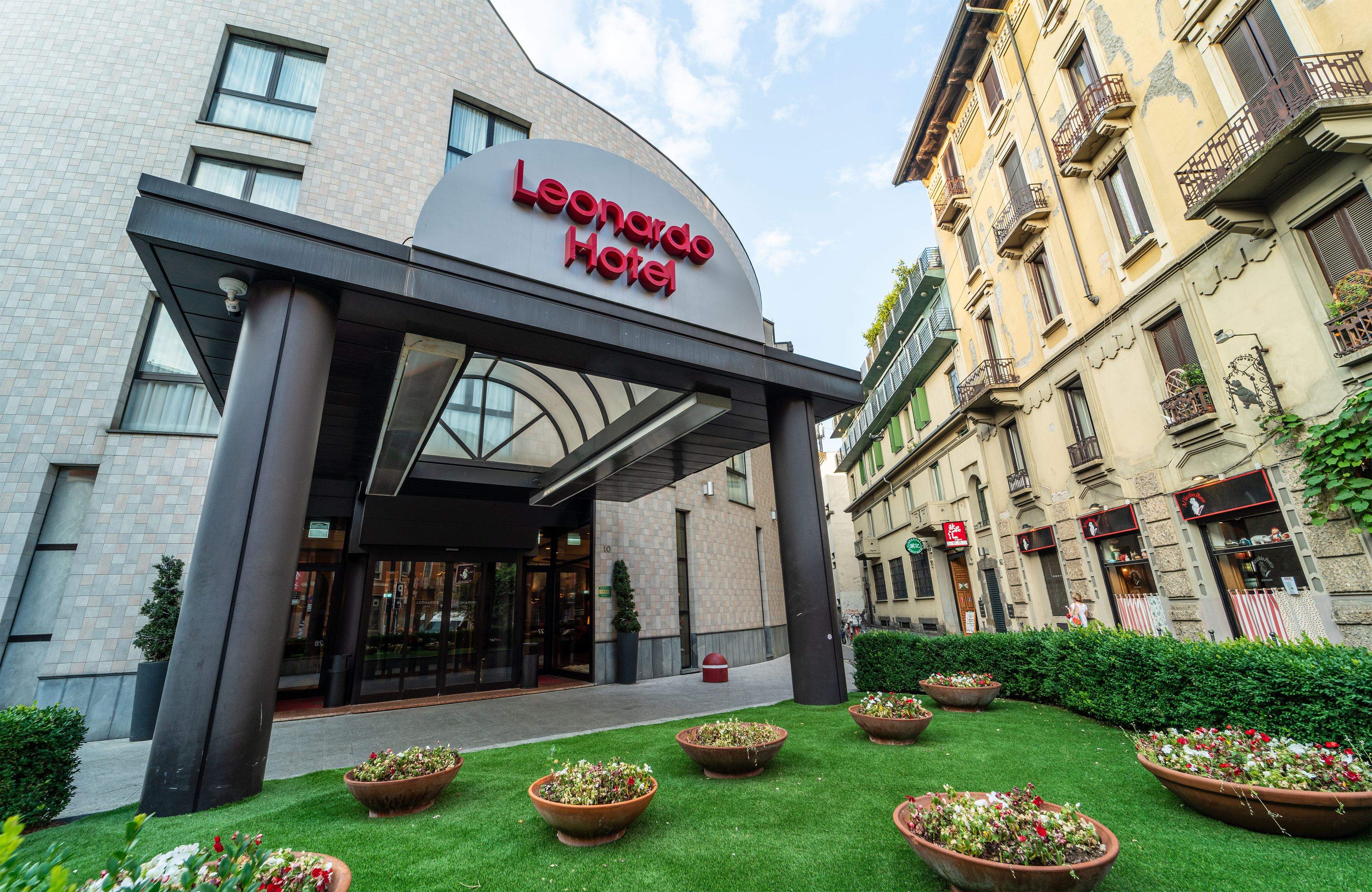 The exterior of the Leonardo Hotel with a modern entrance, a well-maintained lawn, and traditional European architecture.