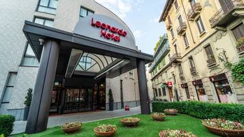 The exterior of the Leonardo Hotel with a modern entrance, a well-maintained lawn, and traditional European architecture.