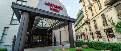 The exterior of the Leonardo Hotel with a modern entrance, a well-maintained lawn, and traditional European architecture.