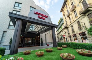 The exterior of the Leonardo Hotel with a modern entrance, a well-maintained lawn, and traditional European architecture. - Leonardo Hotel Milan City Center (Milan)