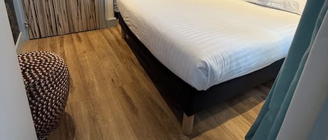 Habitación de hotel con cama, escritorio, silla, piso de madera y un mural con vista a la ciudad.
