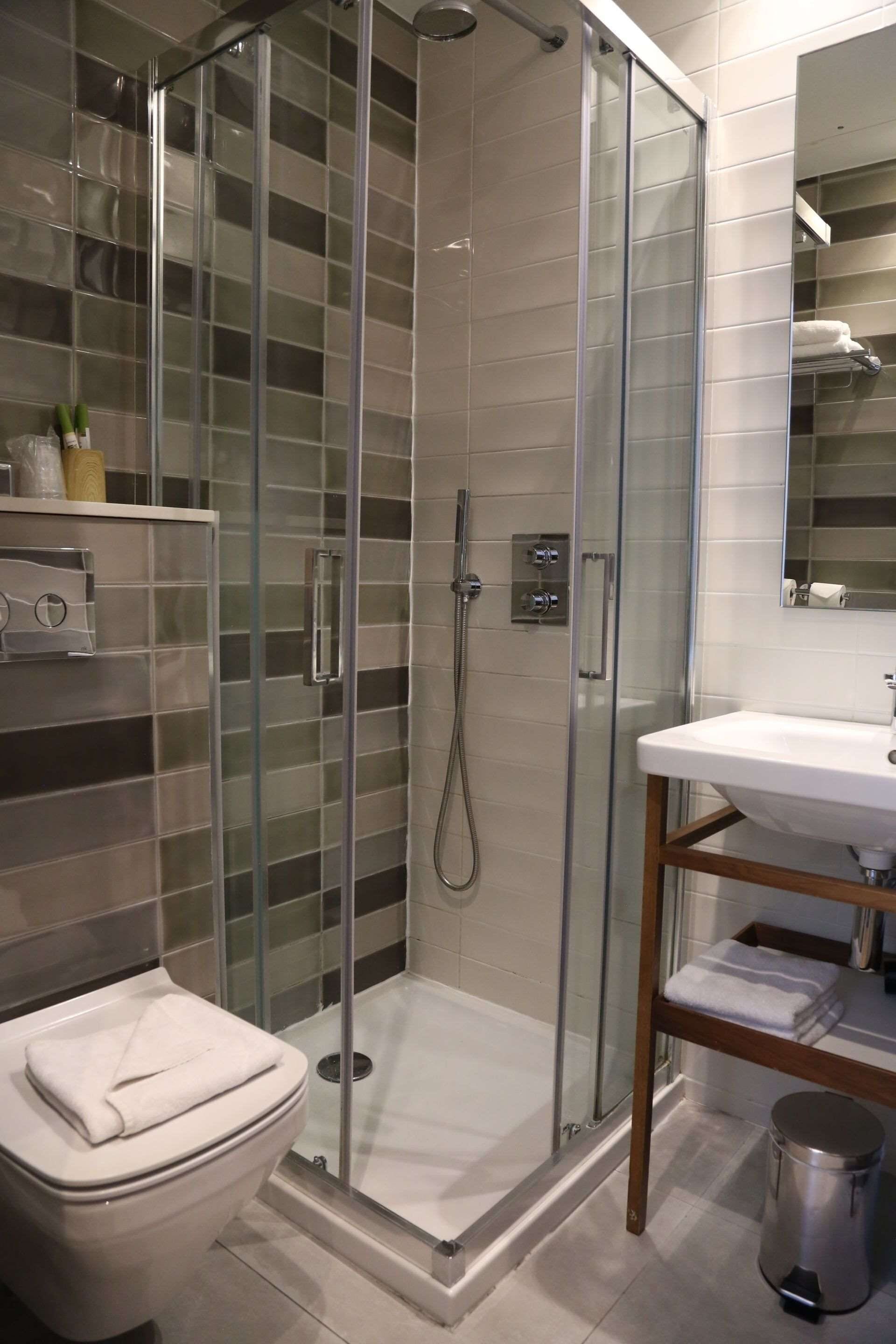 A modern bathroom with a glass-enclosed shower, a white toilet, and a wooden vanity with a sink.