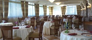 A restaurant with multiple round tables, each set with white tablecloths, chairs, and wine glasses. - Perusia Hotel (Perugia)