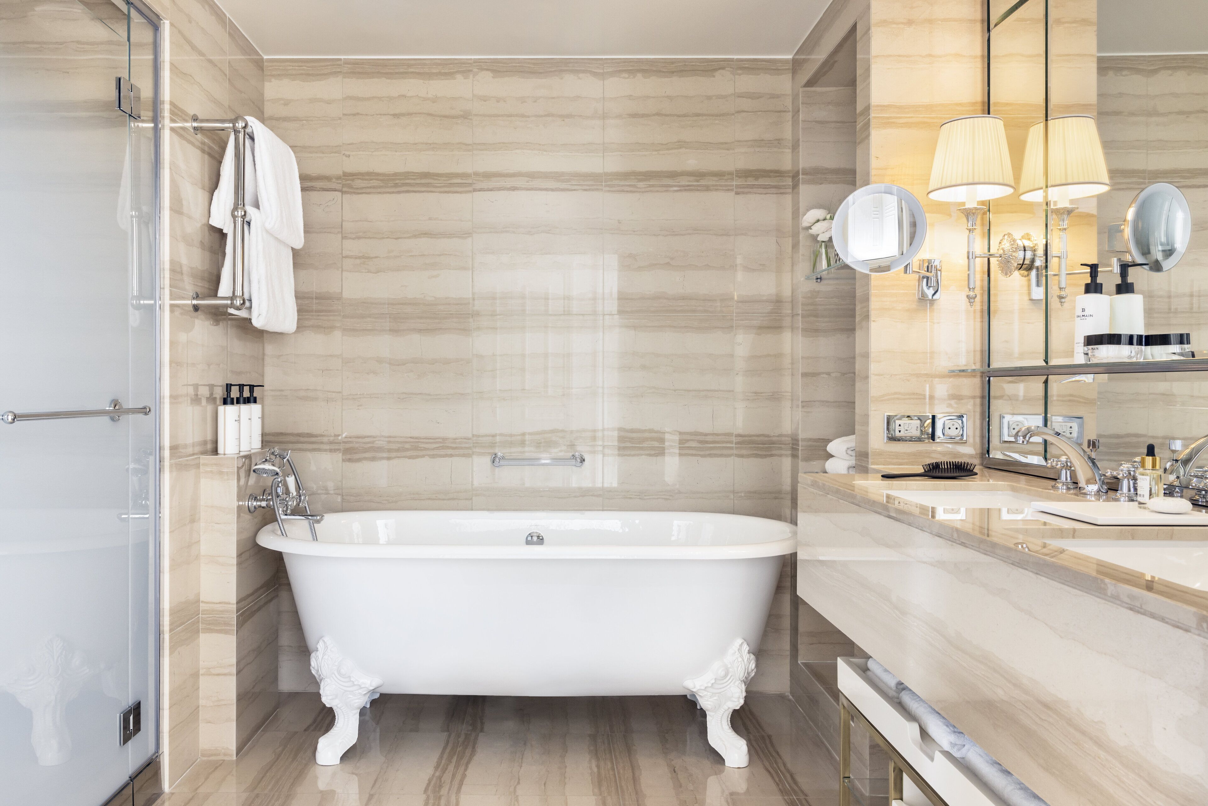 Un baño moderno con una bañera independiente, cabina de ducha con mampara de vidrio y tocador con espejo e iluminación.