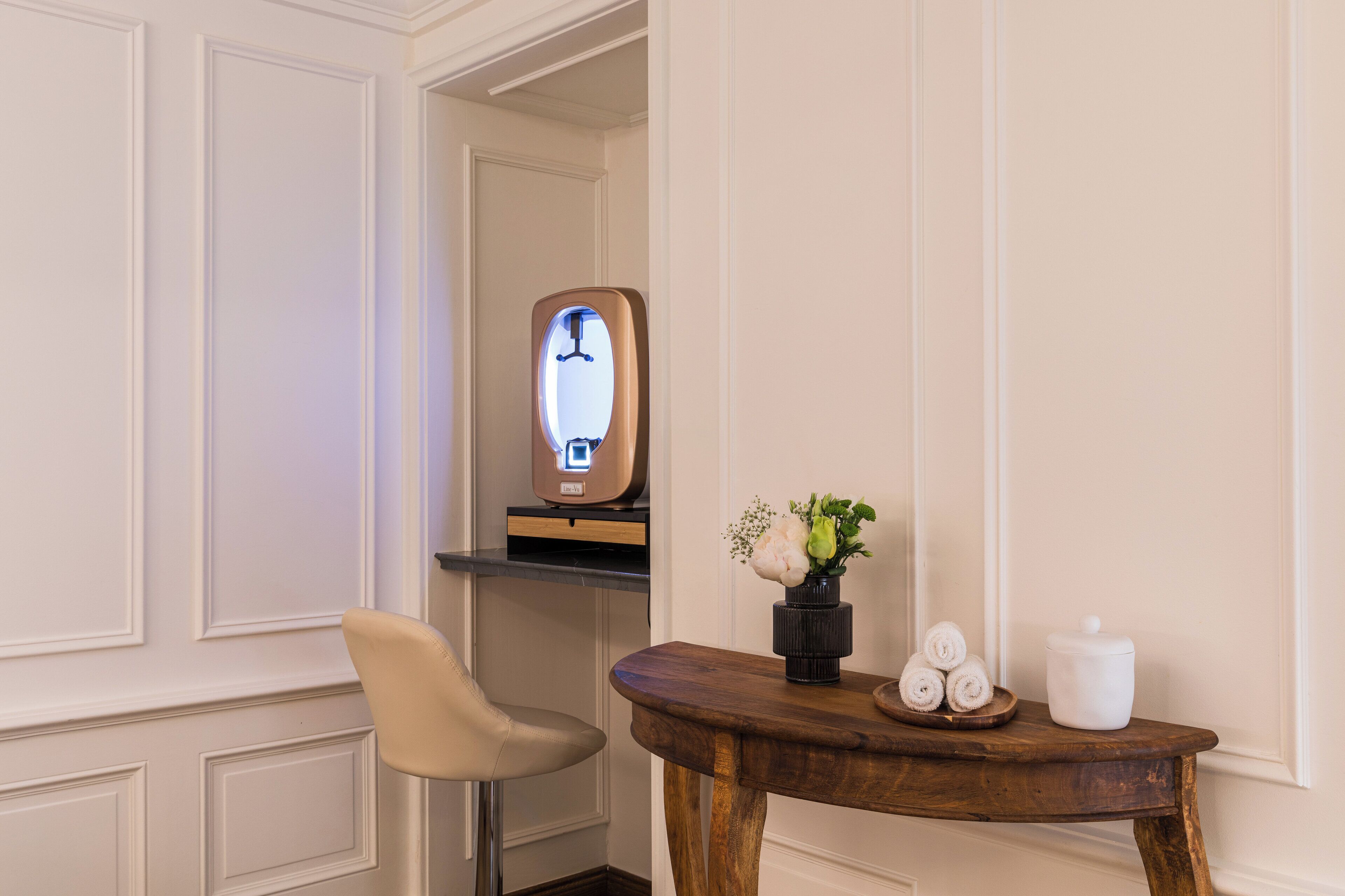 Ein Zimmer mit einem Holztisch, einem Stuhl, einem Spiegel und einer Vase mit Blumen.