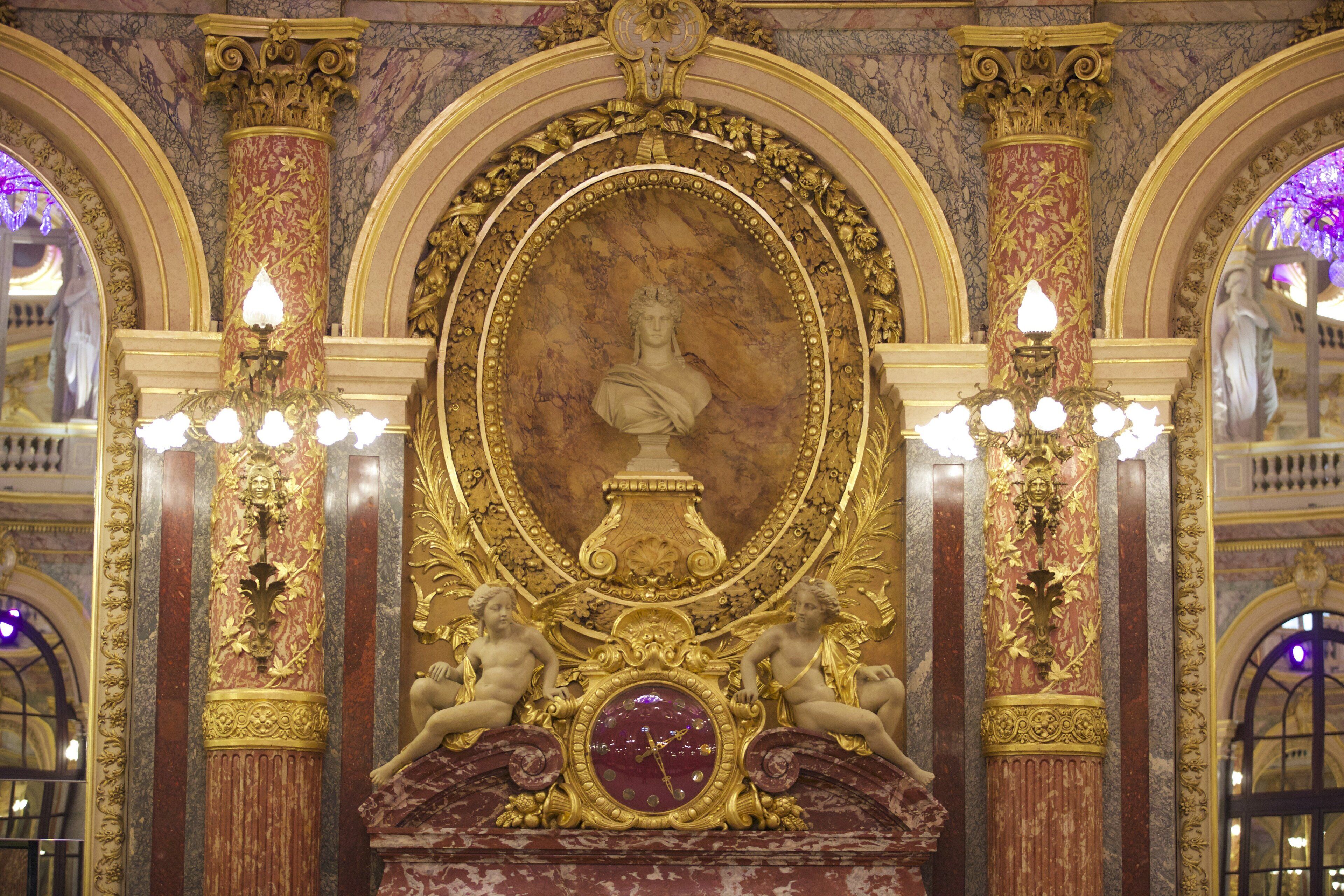 Un intérieur richement décoré, avec un buste central, flanqué de colonnes et d’éléments décoratifs.