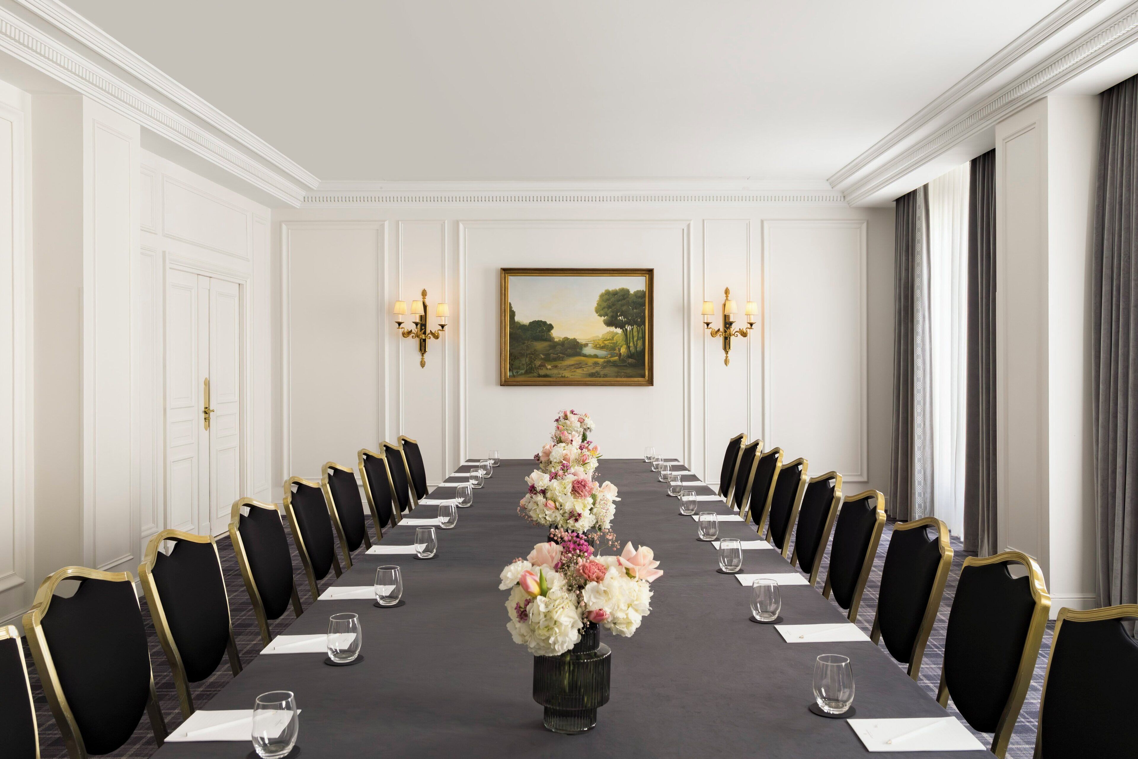 A conference room with a long table, chairs, and a floral centerpiece.