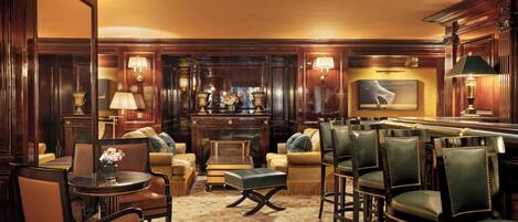 A well-appointed lounge area with leather chairs, a bar, and a fireplace.