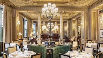 A luxurious dining area with ornate chandeliers, elegant table settings, and classic architecture.