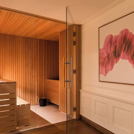 A modern interior with a wooden slatted wall, a glass partition, and a large abstract painting.