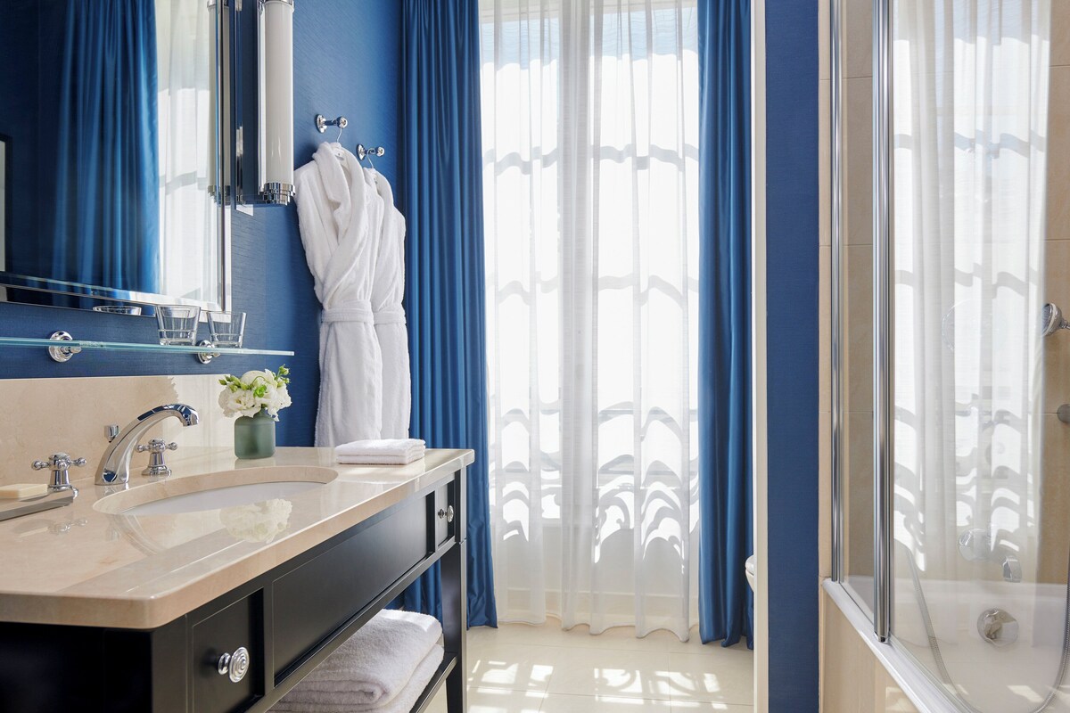 A bathroom with a bathtub, a shower, and a vanity with a mirror.