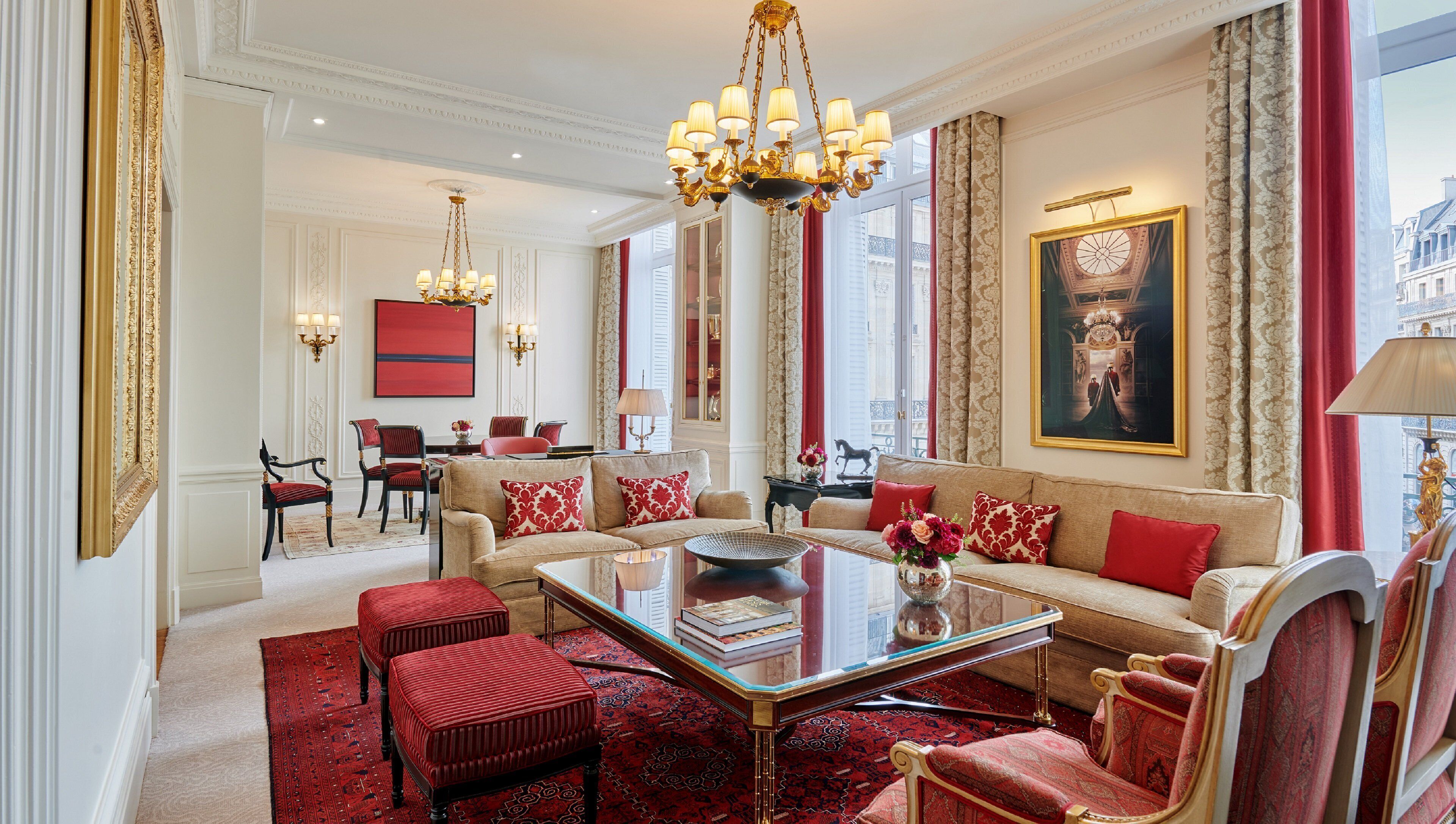 Un salon luxueux, agrémenté d’un lustre, d’une décoration aux tons rouge et or, et d’un grand tableau.