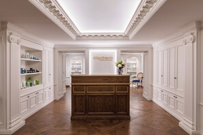 A reception area with a central desk, white cabinetry, and a sign for Algotherm.
