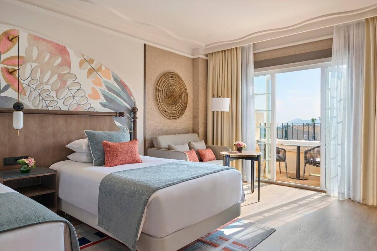 Une chambre d’hôtel avec un grand lit, un canapé, une petite table et un balcon avec vue.