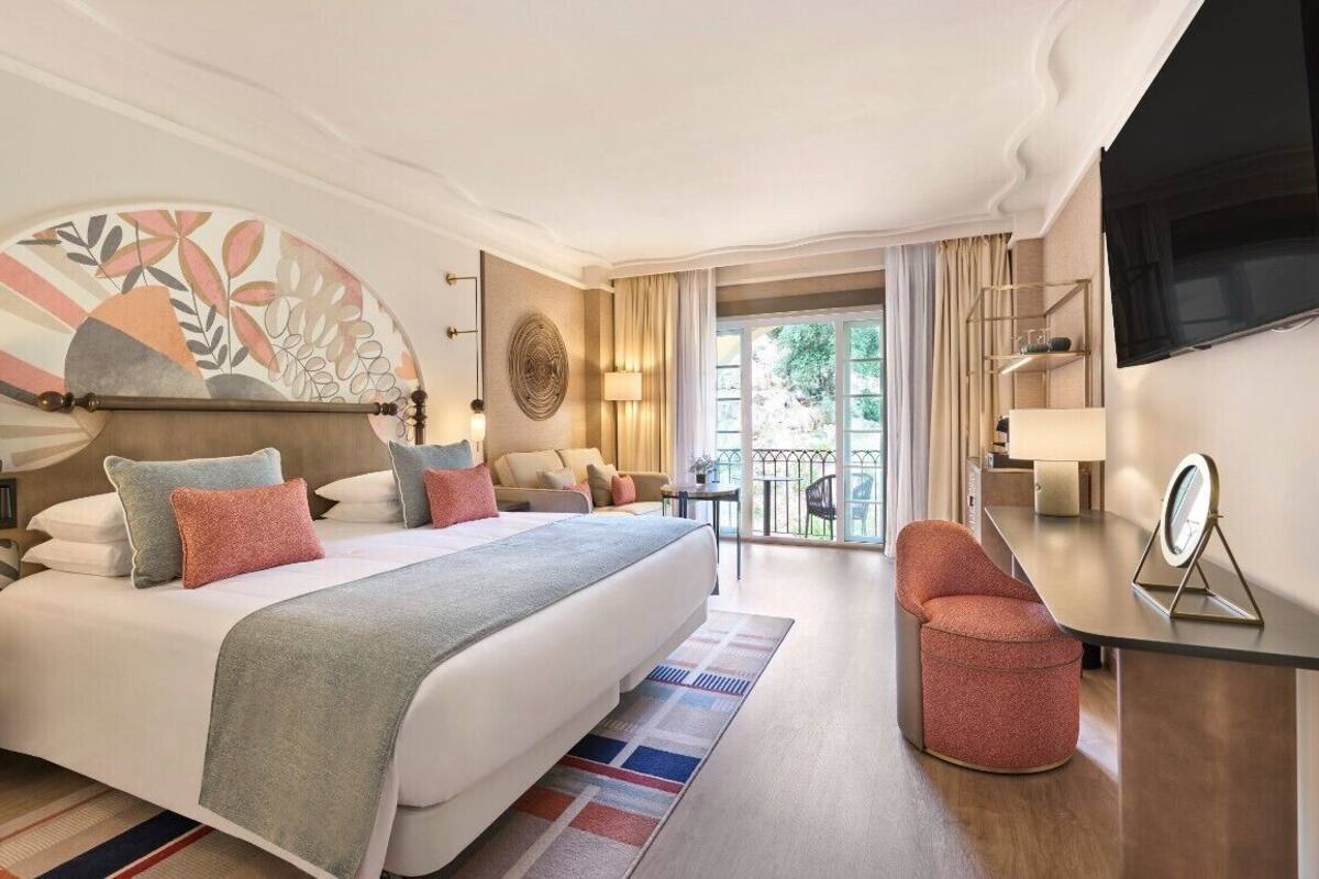 Une chambre d’hôtel moderne dotée d’un grand lit, d’un bureau, d’une chaise et d’un balcon avec vue.