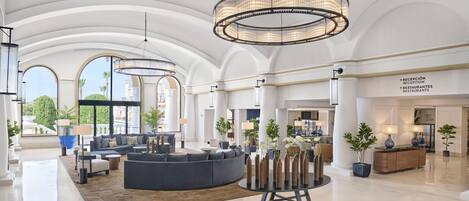 A spacious lobby with a large seating area, a reception desk, and a view of the outdoors.