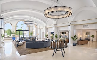 A spacious lobby with a large seating area, a reception desk, and a view of the outdoors.