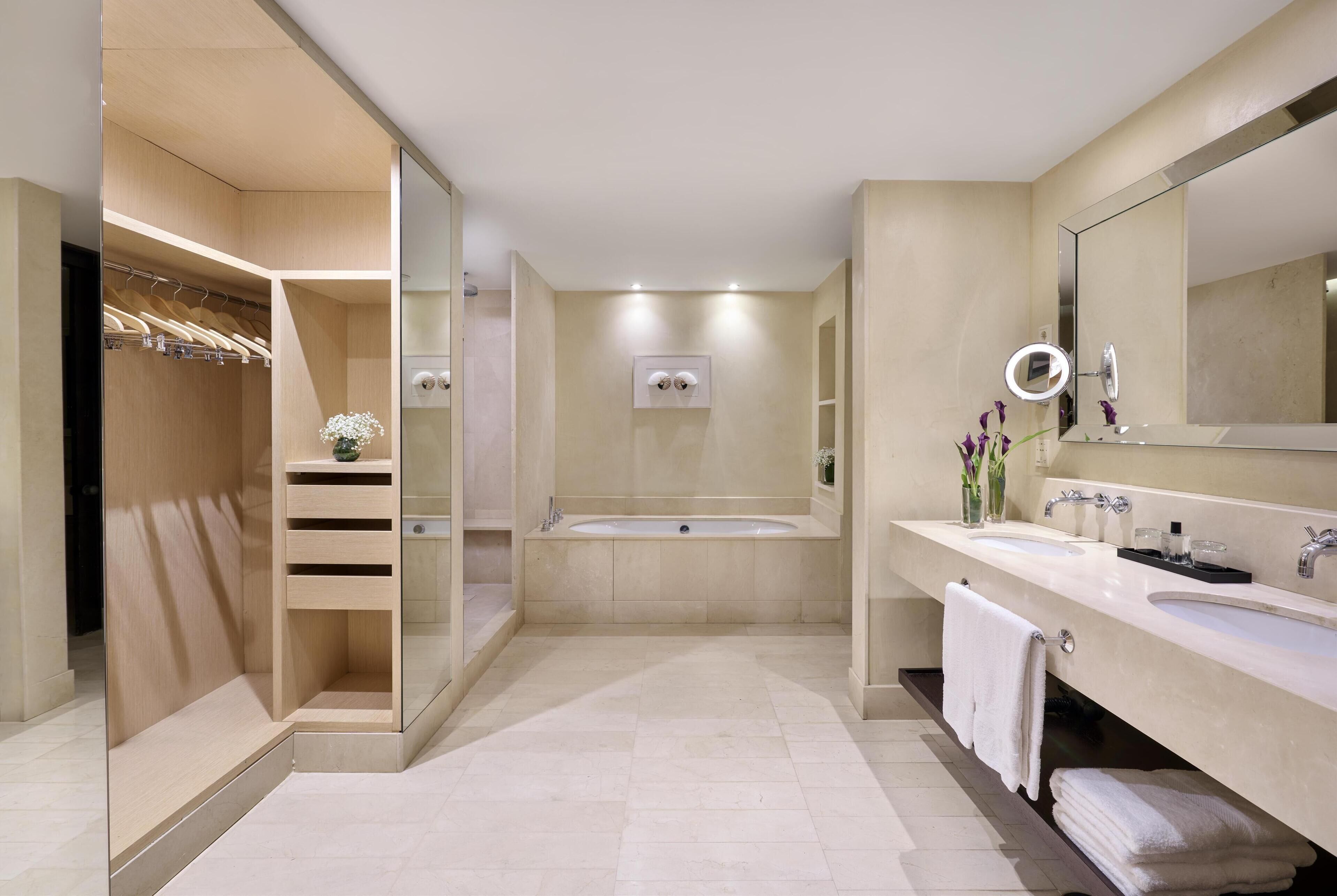 Un baño moderno con ducha a nivel del suelo, una bañera y un tocador con un espejo grande.