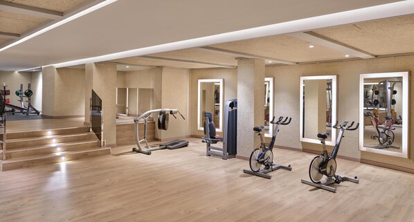 A modern gym with cardio machines, a weight bench, and a staircase leading to upper floors. - Grand Hyatt La Manga Club Golf & Spa (Cartagena)