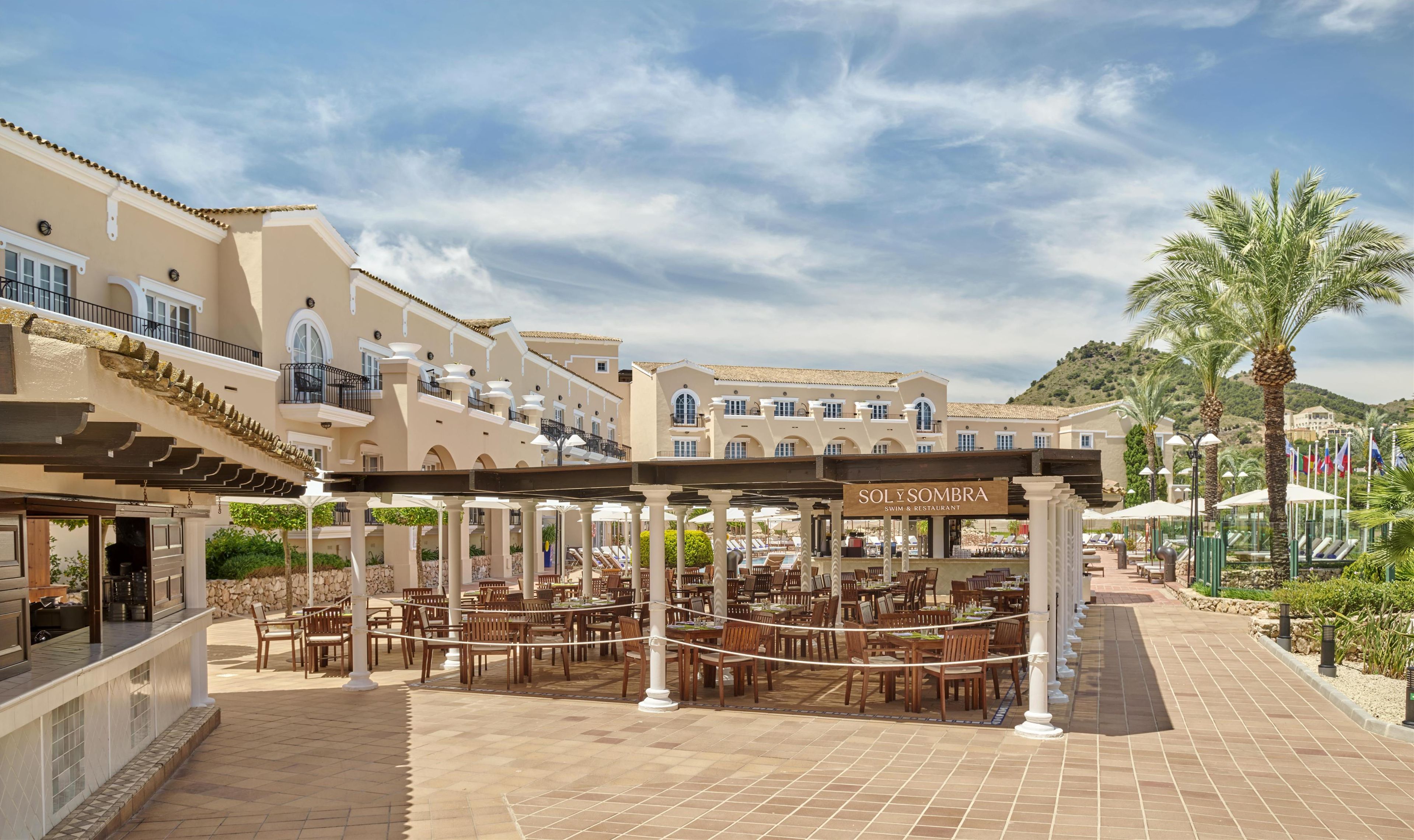 Un complejo turístico con zonas de comedor al aire libre, piscina y un restaurante llamado Soly Sombra.