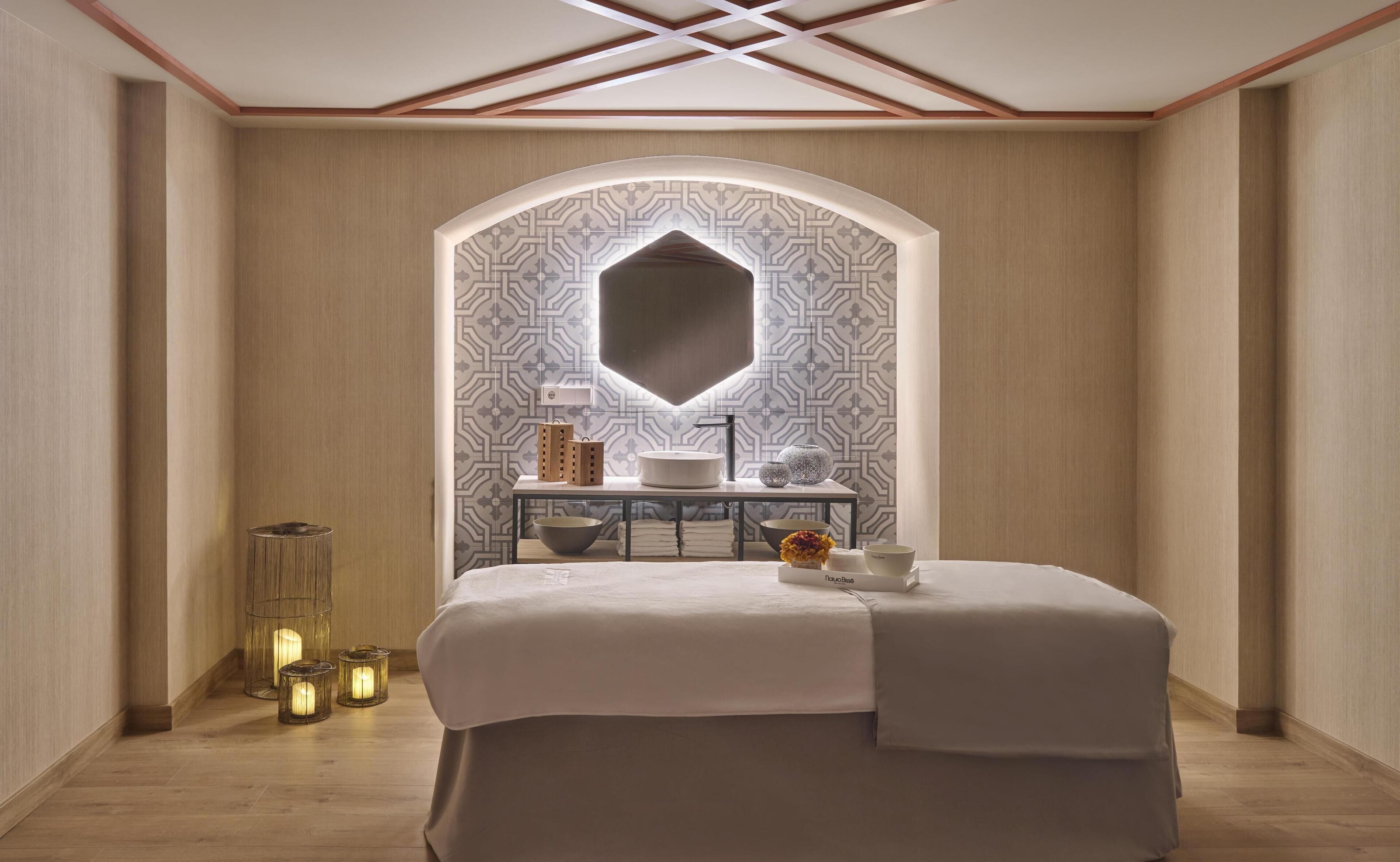 A modern bedroom with a large bed, a vanity with a mirror, and a patterned wall.