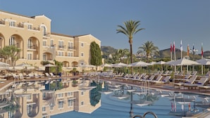 Ein Hotel mit Poolbereich, Liegestühlen, Sonnenschirmen und Flaggen.