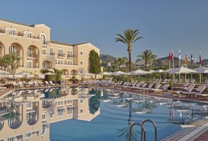 Una piscina al aire libre, sombrillas, sillones reclinables de piscina