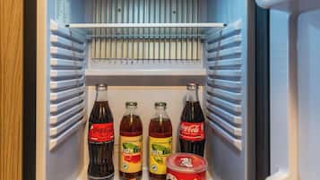 A refrigerator stocked with beverages, snacks, and a box of crackers.